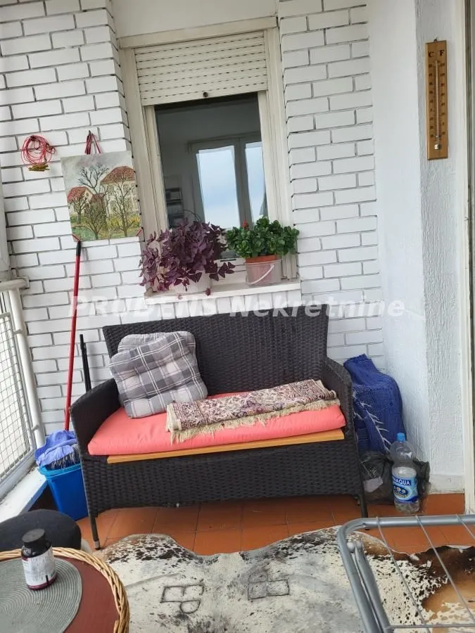 Nameštena terasa sa garniturom za sedenje i ukrasnim biljkama.