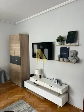 Dnevna soba sa TV komodom, garderoberom i policama na zidu. - image 5