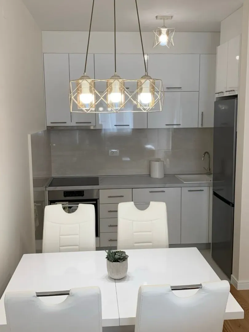 Modern white kitchen with a dining table and chairs.