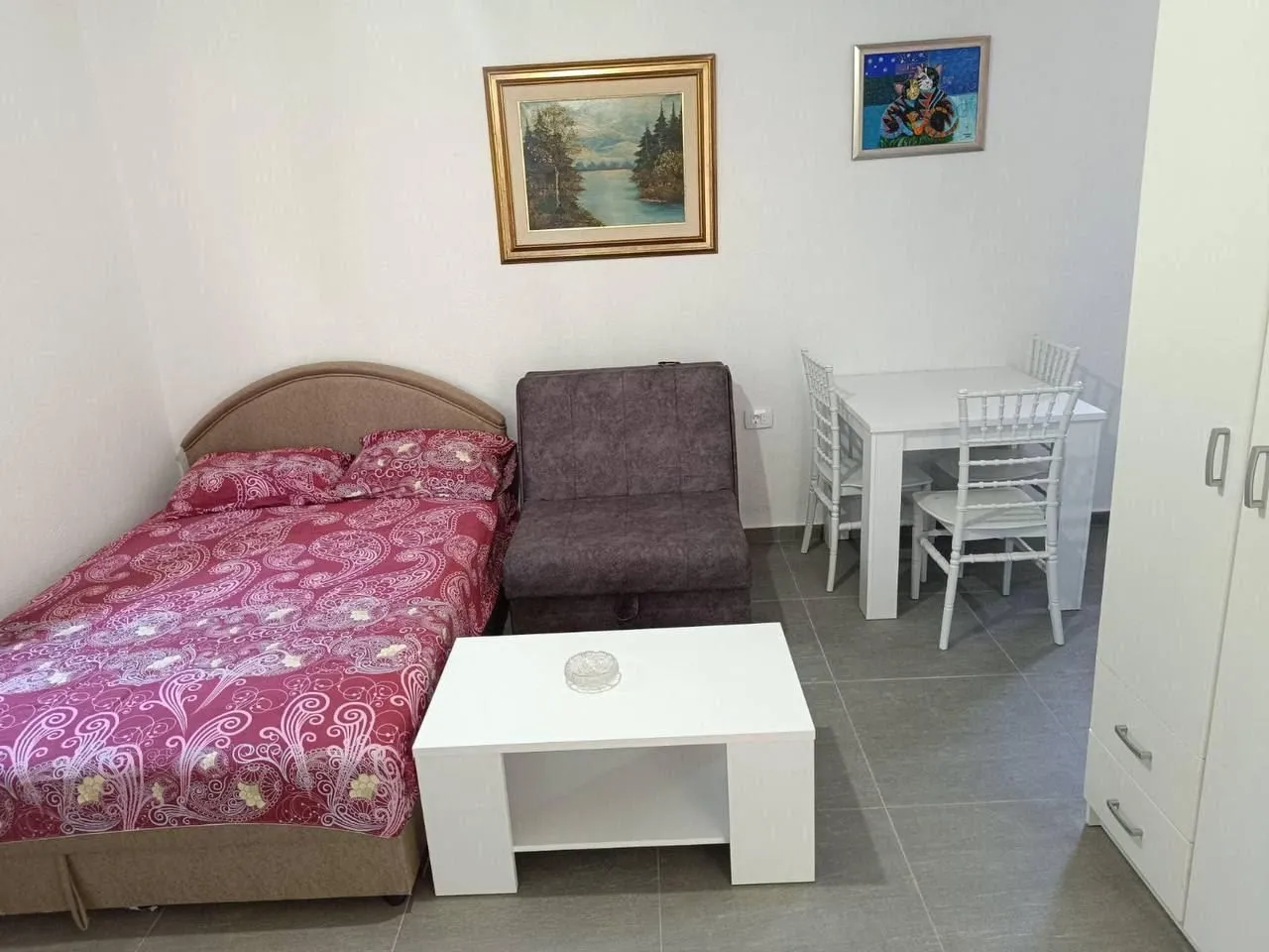 Furnished bedroom with a bed, armchair, and dining table.