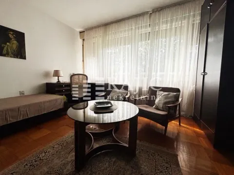 Living room with seating furniture, a desk, and a large window. - image 2
