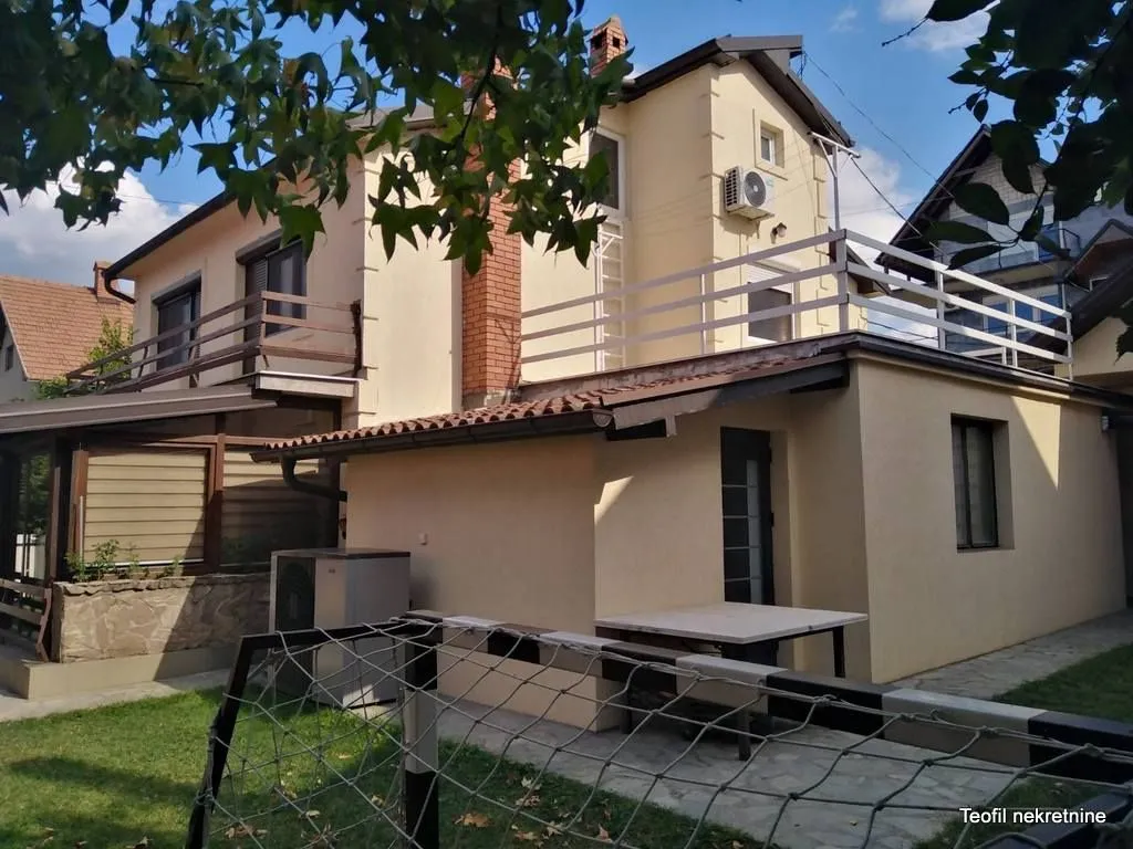 Pogled na spoljašnjost kuće sa dvorištem i terasom.