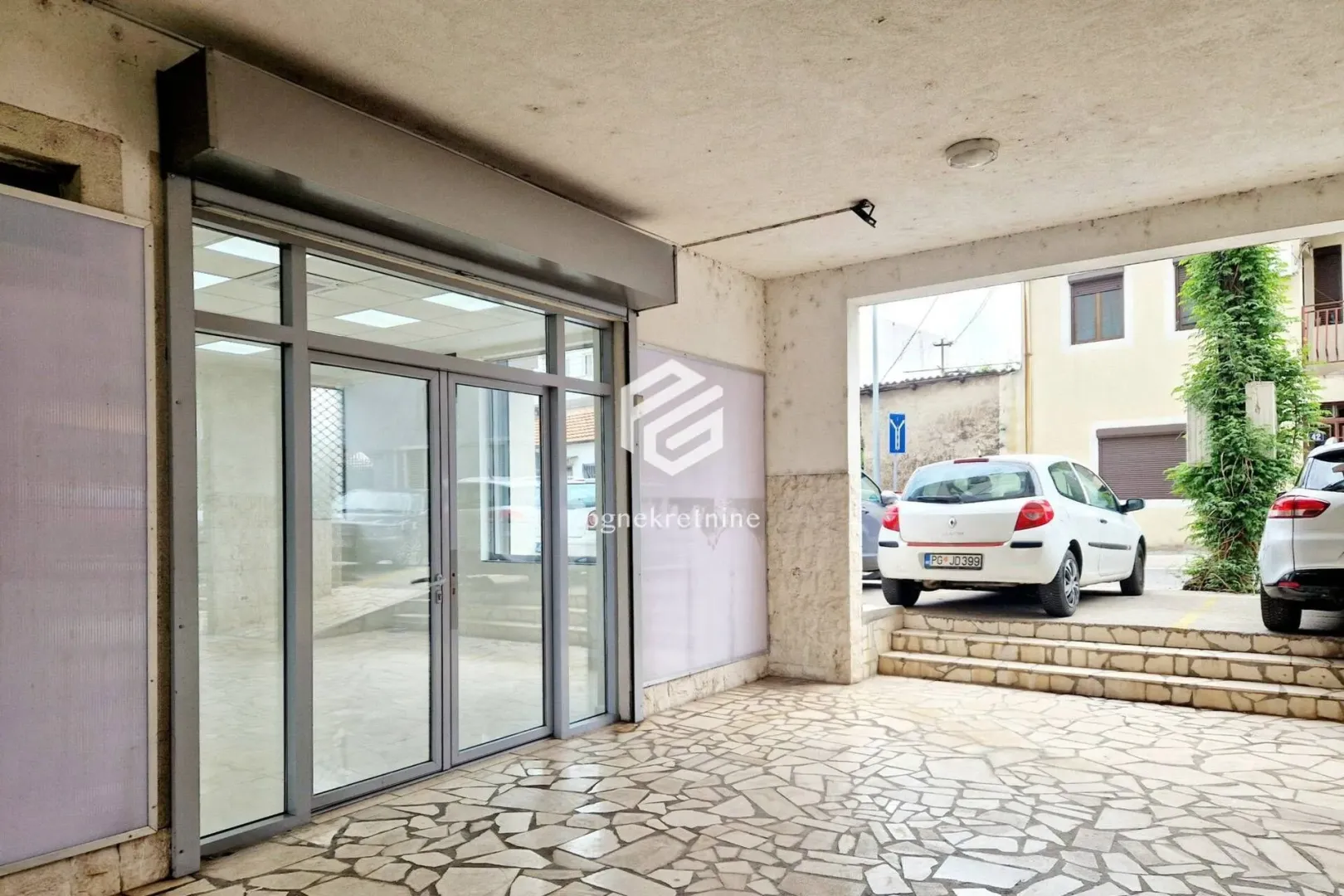 Entrance to the commercial space with a glass storefront and paved yard.