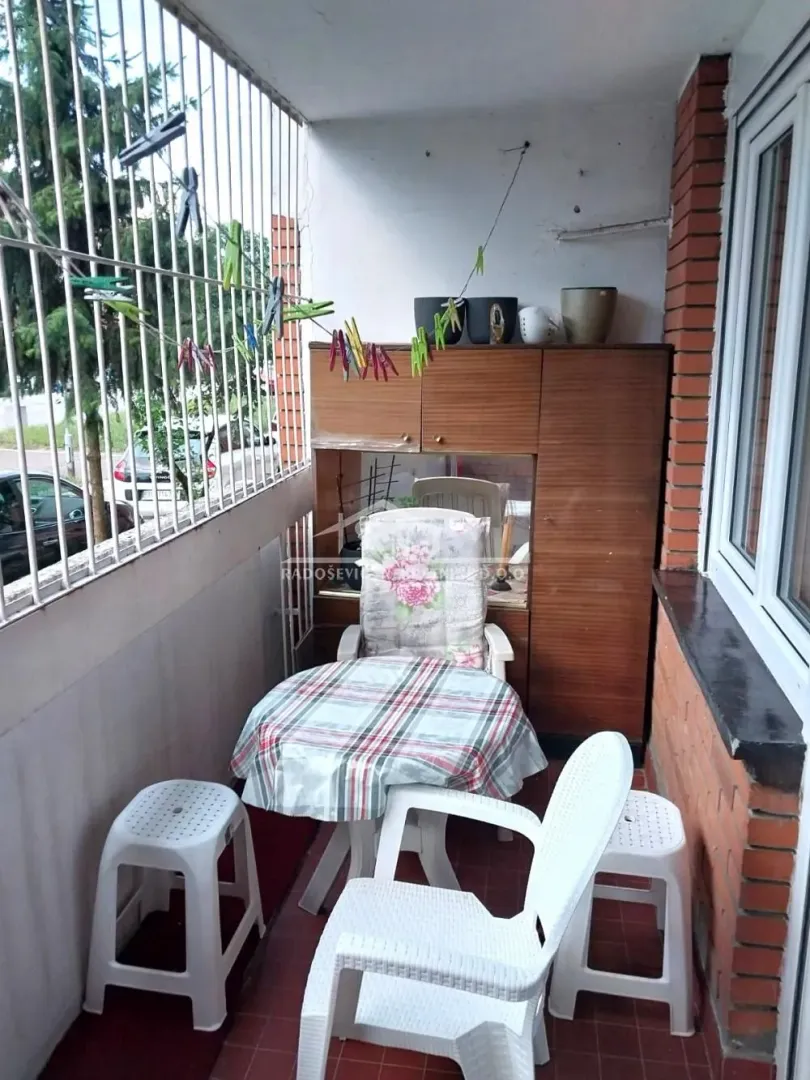 Natkriveni balkon sa garniturom za sedenje i ugrađenim ormarom.