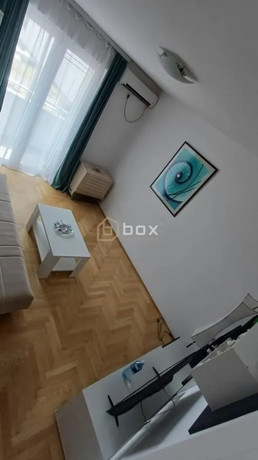 Living room with a sofa, coffee table, and parquet flooring.