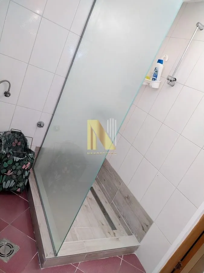 Moderno kupatilo sa tuš kabinom i keramičkim pločicama.