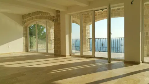 Spacious empty room featuring stone arches, large glass doors, and a sea view. - image 8