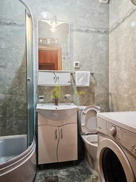 Compact bathroom with a shower cabin, washbasin, toilet, and washing machine. - image 5