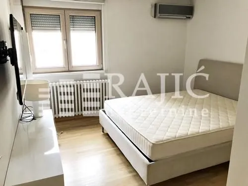 Furnished bedroom with a double bed, chest of drawers, and air conditioning.