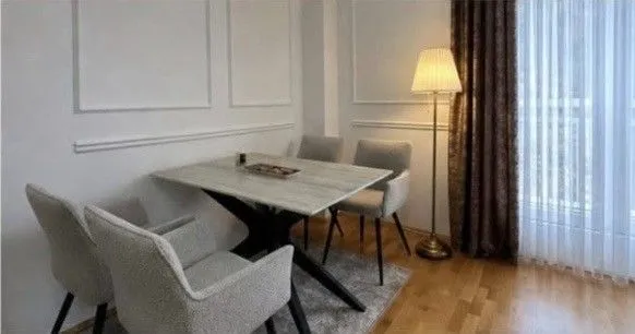 Trpezarijski kutak sa stolom, četiri stolice i podnom lampom.