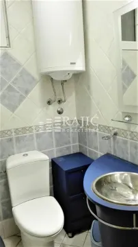 Manje kupatilo sa belim toaletom, plavim umivaonikom i bojlerom na zidu. - image 19