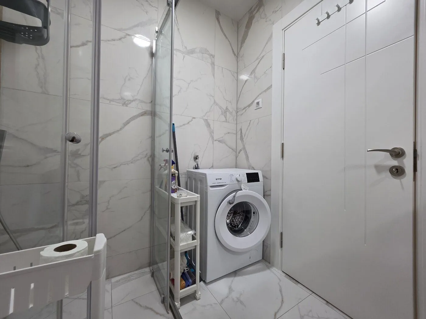 Modern bathroom with a walk-in shower and washing machine.