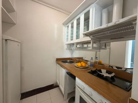 Manja kuhinja sa drvenom radnom površinom i belim kuhinjskim elementima. - image 3