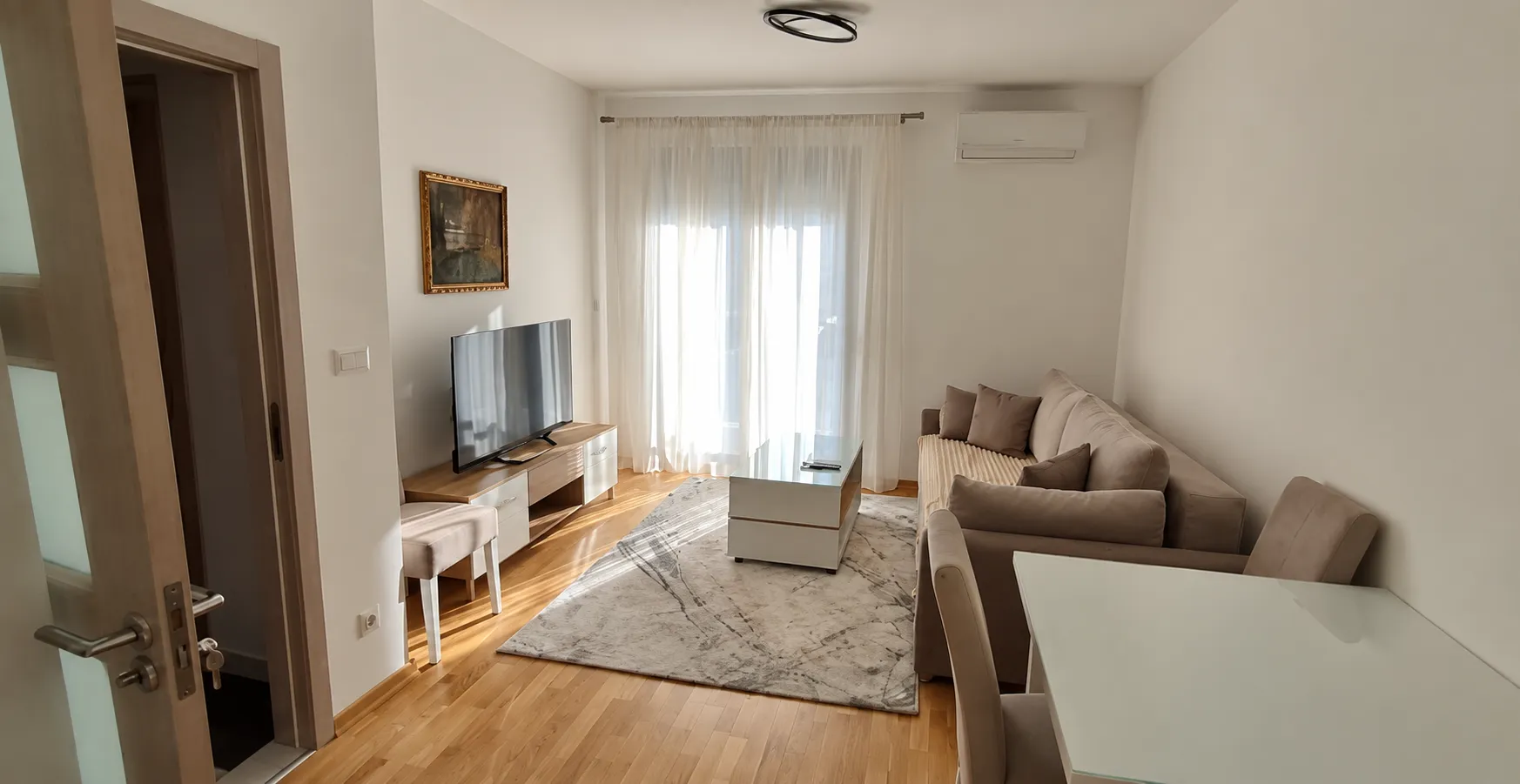 Living room with a sofa, TV unit, and dining table.