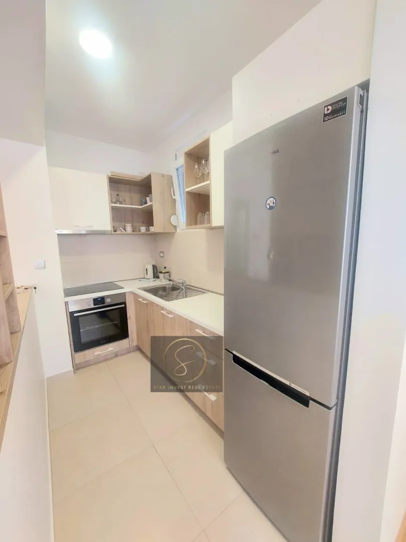 Small modern kitchen with wooden elements and a gray refrigerator.