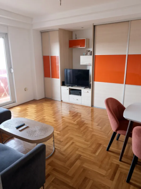 Dnevna soba sa garniturom, TV komodom i parketom na podu.