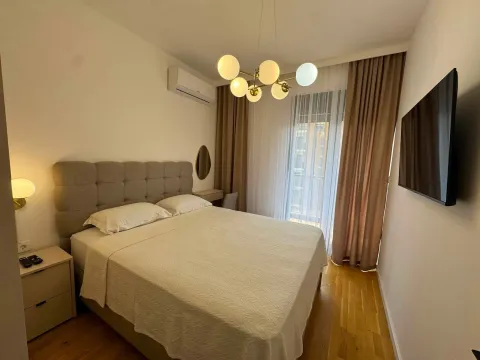 Furnished bedroom with a double bed and wall-mounted TV. - image 9