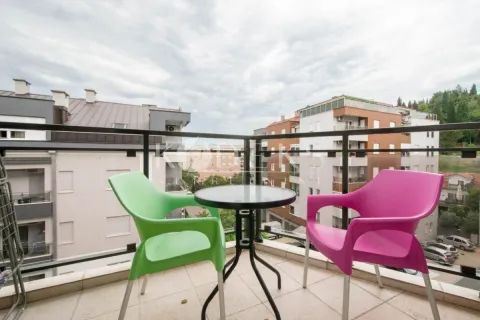 Small furnished balcony with a small table and two colorful chairs, overlooking the neighborhood. - image 9