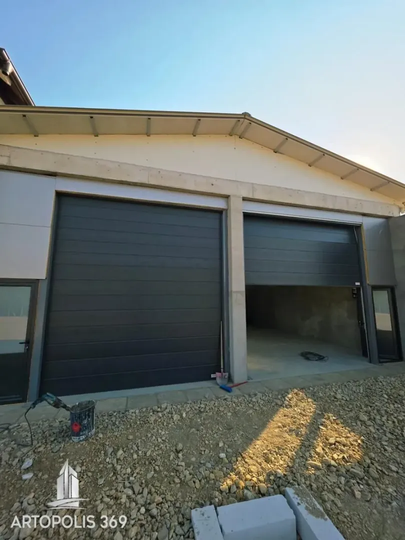 View of the building exterior with garage doors and driveway under construction.