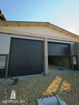 View of the building exterior with garage doors and driveway under construction. - image 2