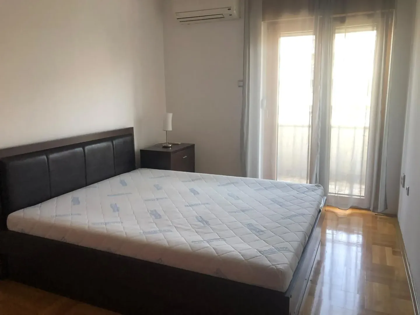 Svijetla spavaća soba sa bračnim krevetom i izlazom na terasu.