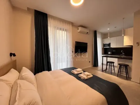 Furnished bedroom with a double bed and an open kitchen in the background. - image 6