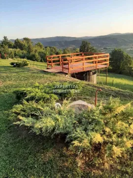 Pogled na drvenu terasu i travnato dvorište sa brdima u pozadini. - image 7