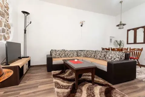 Living room with a sectional sofa, TV, and a dining area in the background. - image 9