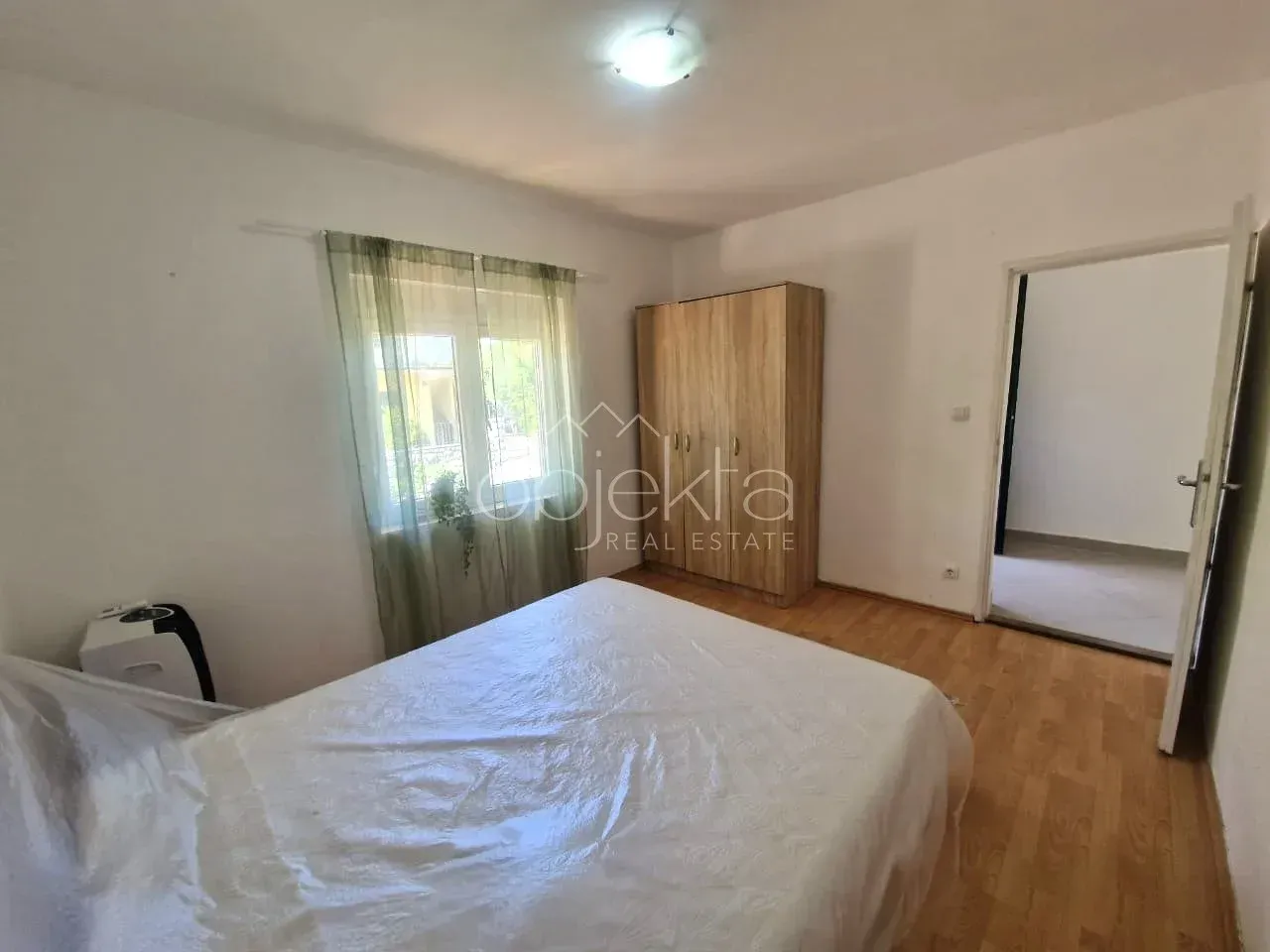 Furnished bedroom with a double bed, wardrobe, and window.