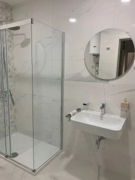 Moderne kupatilo sa tuš kabinom, umivaonikom i okruglim ogledalom. - image 7