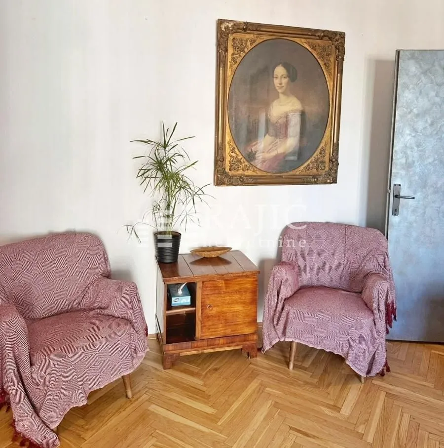 Living room with two armchairs, a small table, and a painting on the wall.
