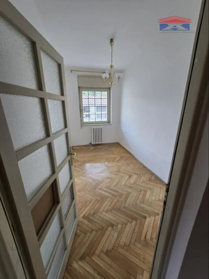 Empty room with hardwood parquet flooring and a window viewed from the doorway.