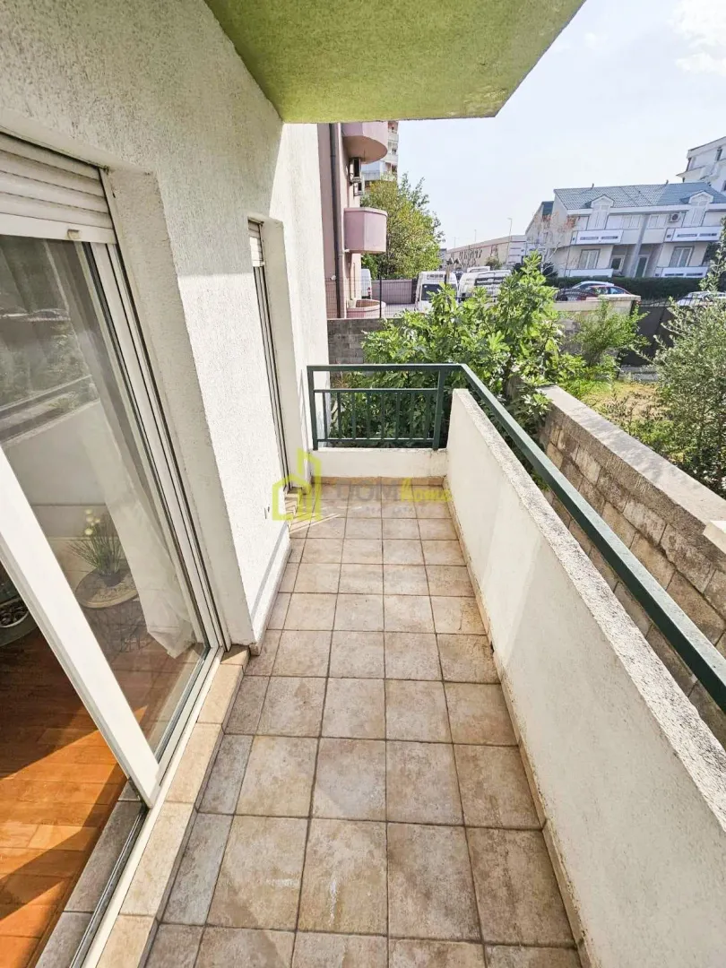Natkriveni balkon sa popločanim podom i pogledom na okolinu.