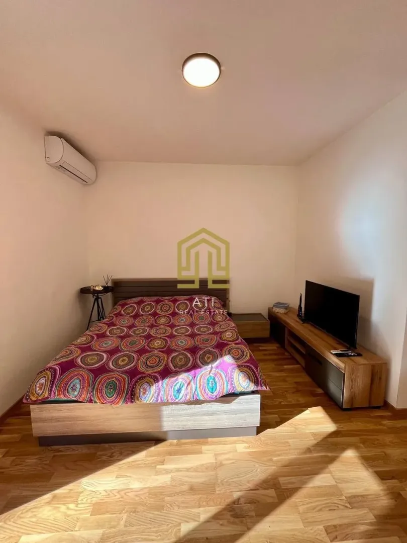 Namještena spavaća soba sa bračnim krevetom, TV komodom i klima uređajem.