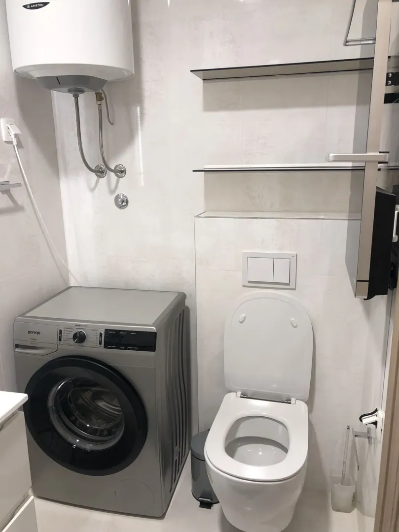Bright bathroom with a washing machine and toilet.