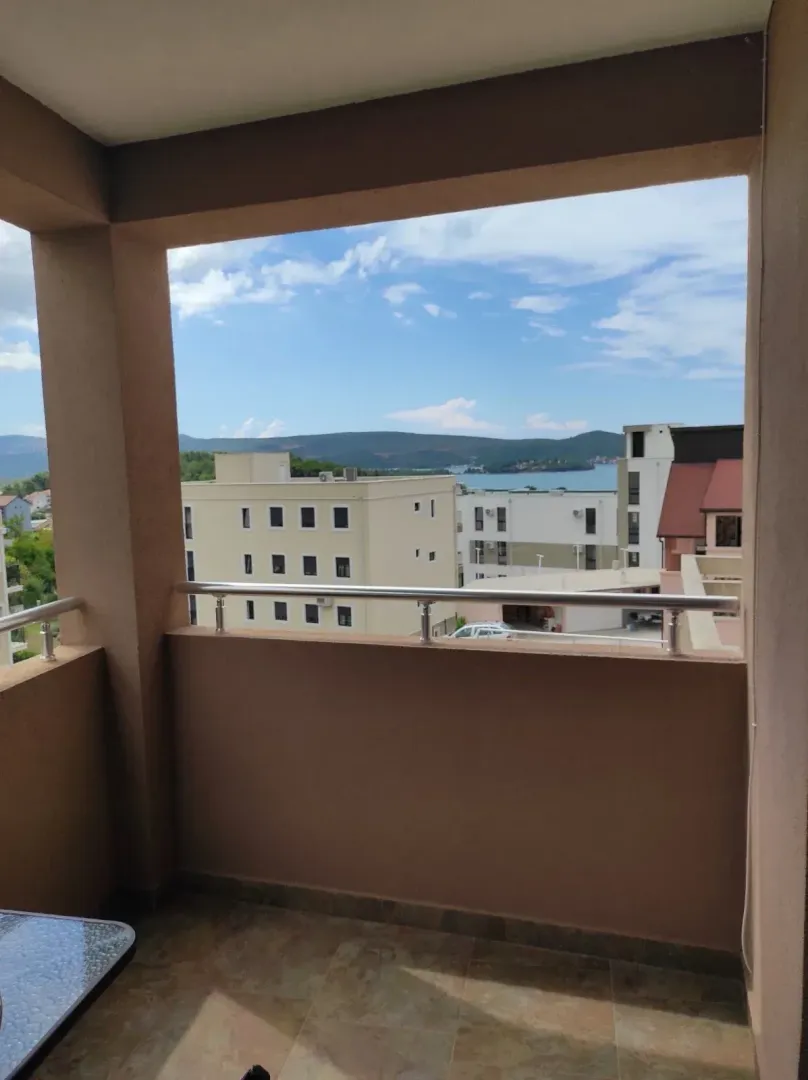 Pogled sa natkrivenog balkona na okolne zgrade i more.