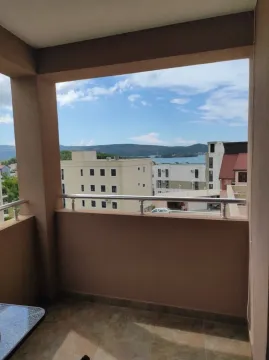 Pogled sa natkrivenog balkona na okolne zgrade i more. - image 4