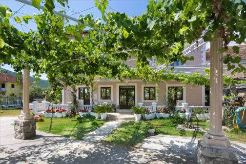 House yard with a grapevine-covered pergola and a landscaped garden. - image 2