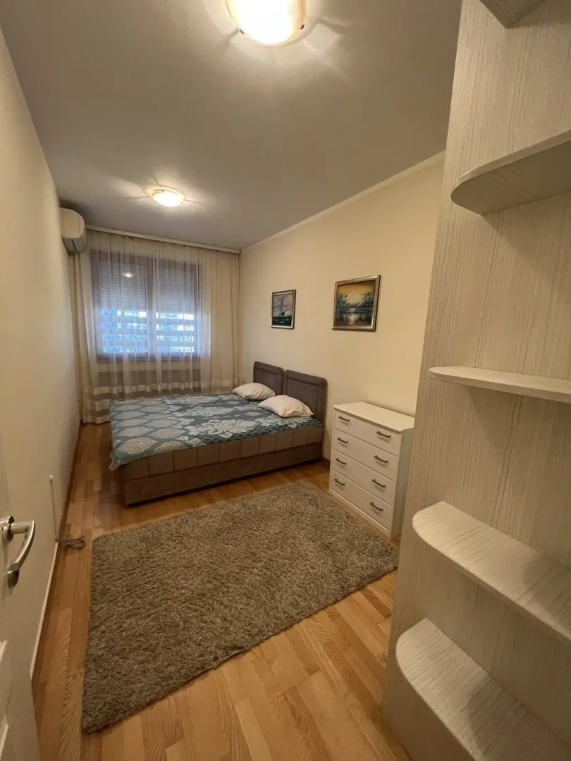 A simply furnished bedroom with a double bed and a chest of drawers.