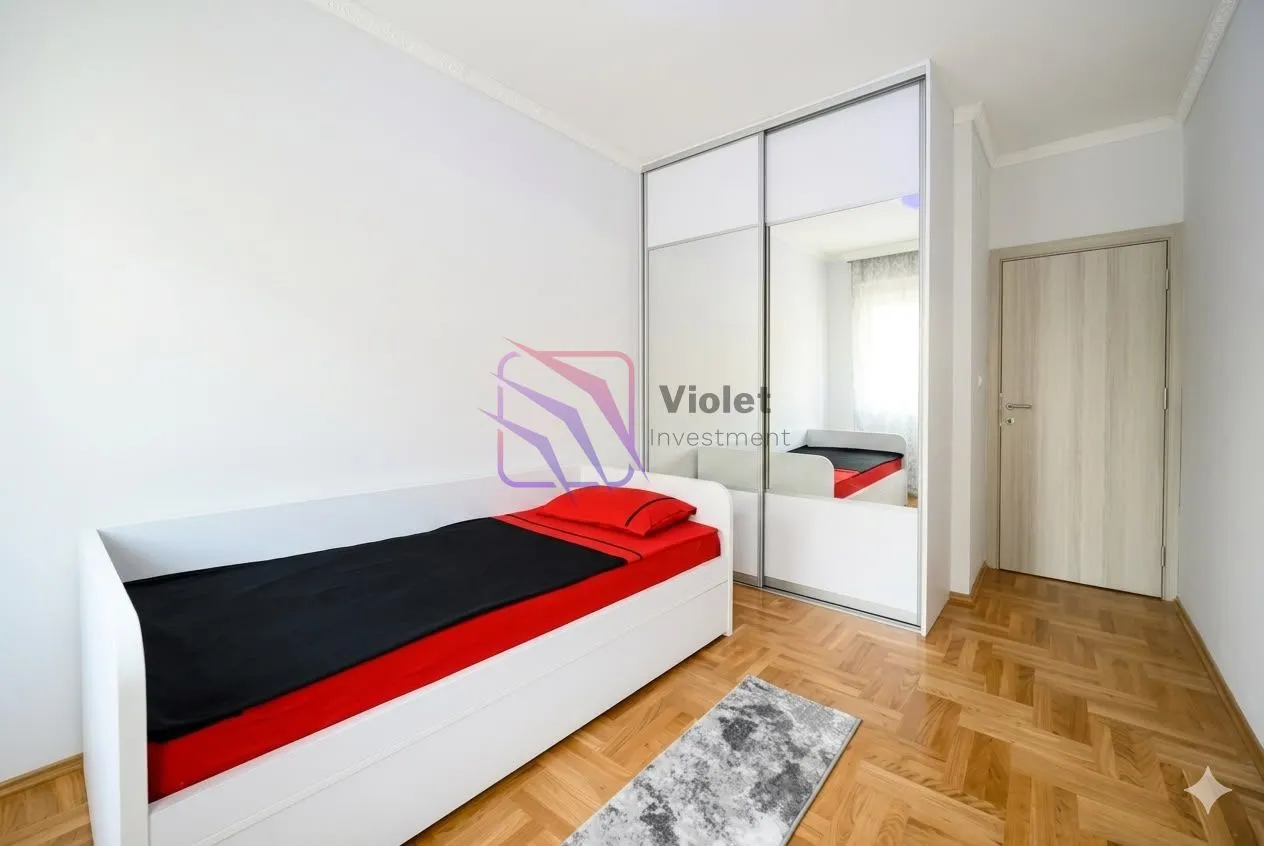 Small bedroom with a bed, a large mirrored wardrobe, and parquet flooring.