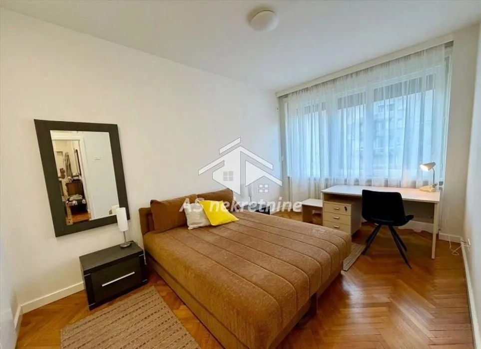 Furnished bedroom with a double bed and a desk.