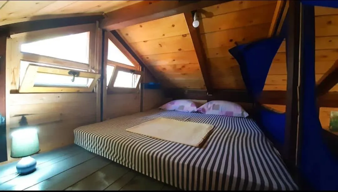 Potkrovlje opremljeno kao spavaća soba sa drvenim oblogama i krevetom.
