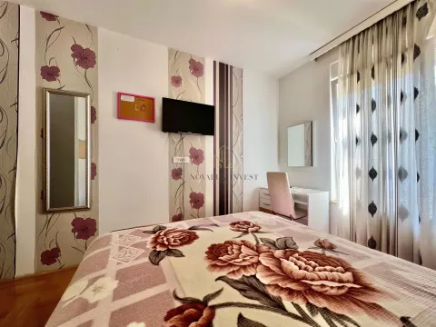 Furnished bedroom with a double bed, a desk, and a wall-mounted TV. - image 9