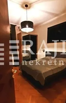 Nameštena spavaća soba sa bračnim krevetom i ormarom.