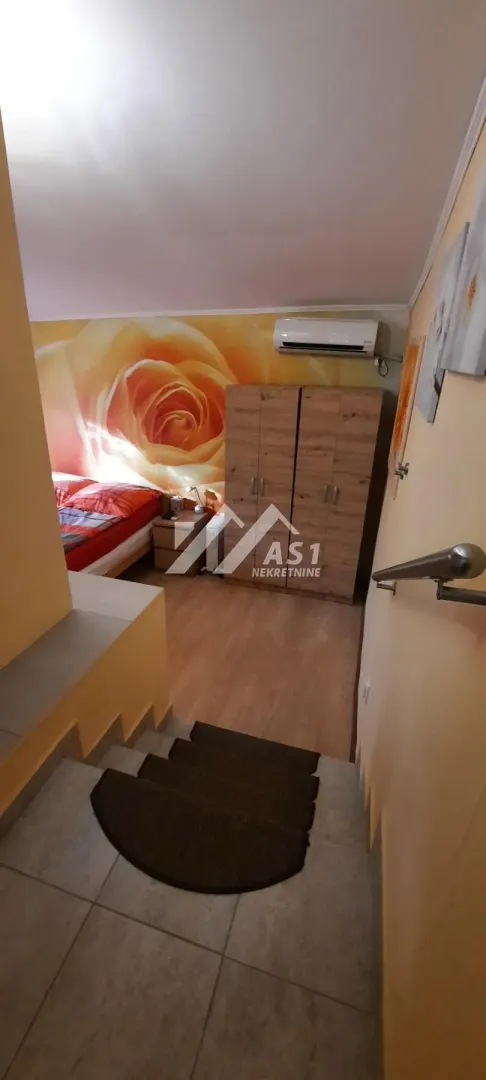 Pogled iz stepeništa prema spavaćoj sobi sa bračnim krevetom i garderoberom.
