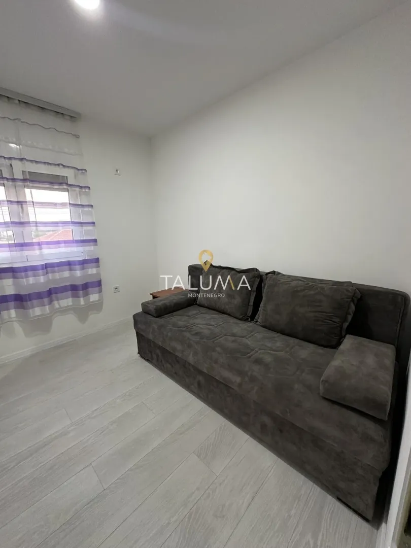 Living room with a grey sofa and a window with purple curtains.