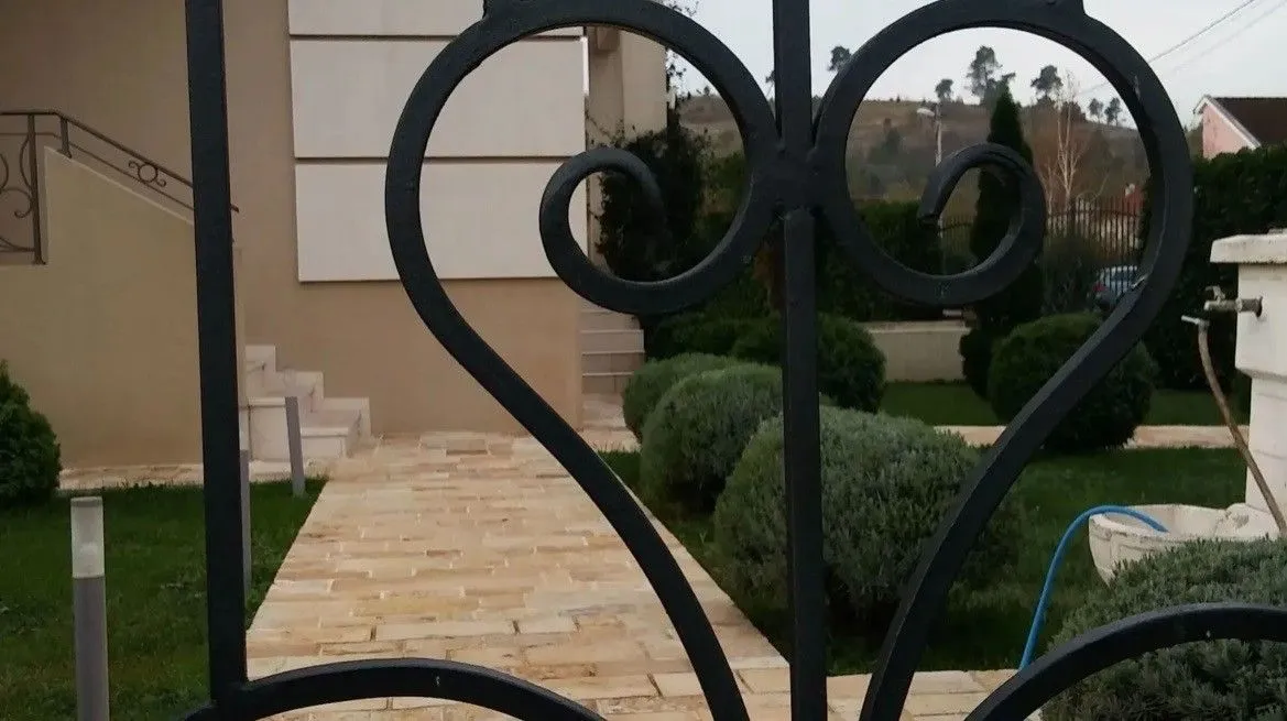 View of the yard and walkway through an ornamental metal gate.