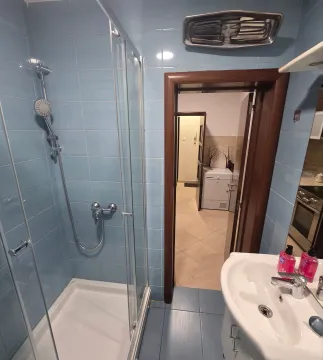 Manje kupatilo sa tuš kabinom, umivaonikom i plavim zidnim pločicama. - image 4
