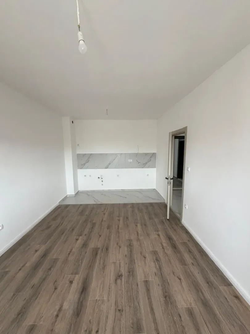 Empty room intended for a kitchen with installed tiles and wooden flooring.