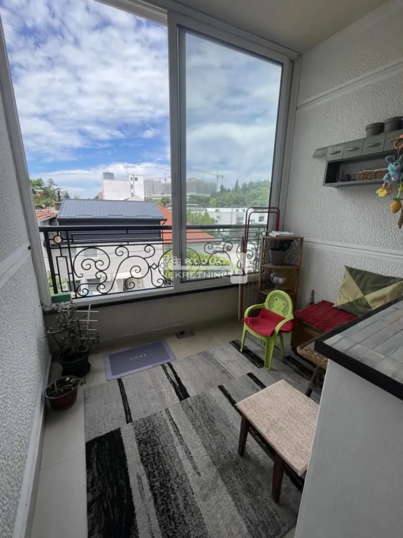 Glazed terrace with a rug, small table and chairs, and a view of the surroundings.